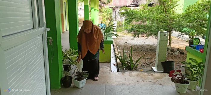 Guru MIN 4 Batang Hari Elia, S.Pd. Rawat Keindahan Sekolah dengan Menyiram Bunga