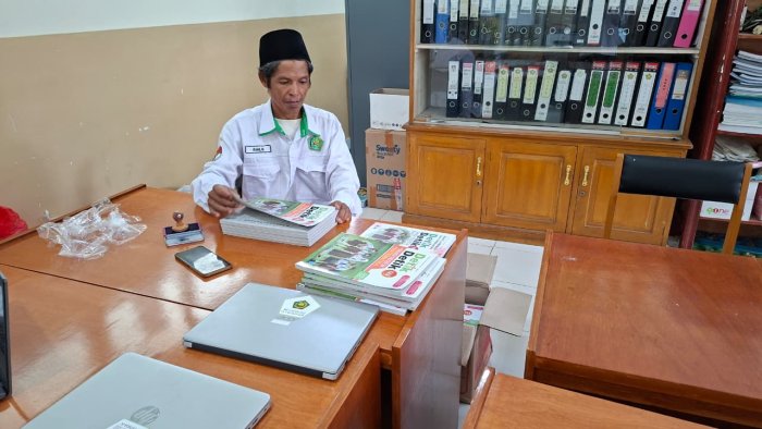 Staf TU Ramlan Memberi Stempel pada Buku Cetak Inventaris Madrasah